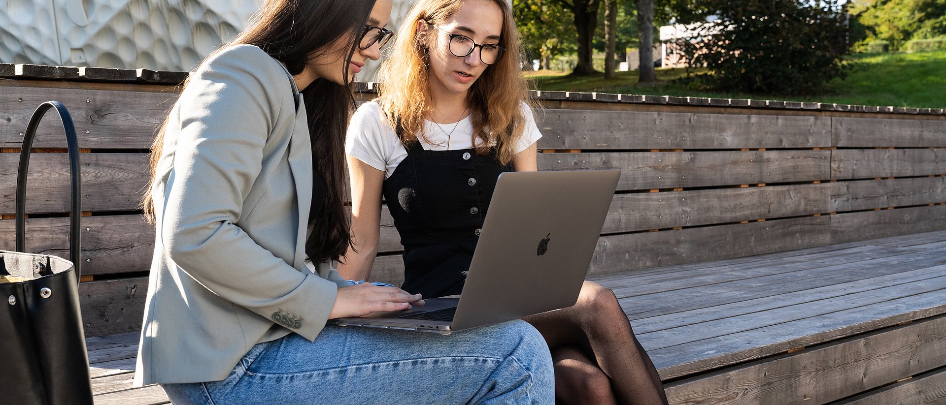 Two people sitting outside working on a laptop.