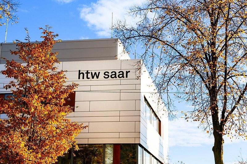 Eckansicht eines weißen Gebäudes mit Schriftzug „htw saar“.