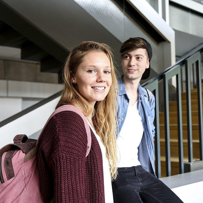 Two people standing in front of stairs looking at the camera.