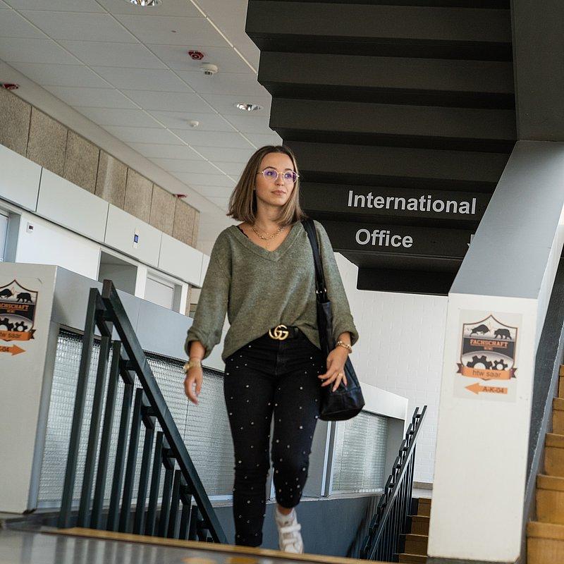 Person walking up stairs with the sign “International Office.”