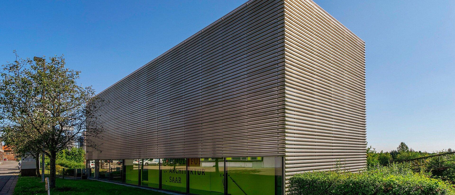 Modern building with metal facade and long window strips on the ground floor.