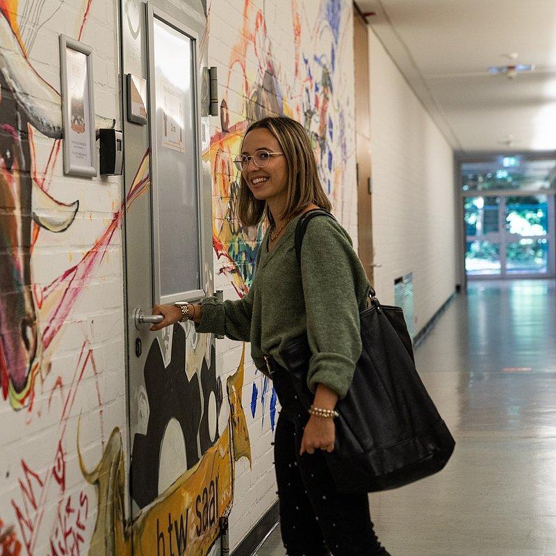 Person opening a door next to a mural with a bull motif.