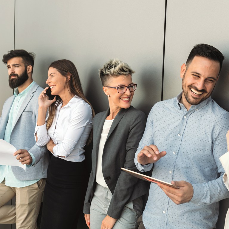 Four people standing side by side, laughing and talking.