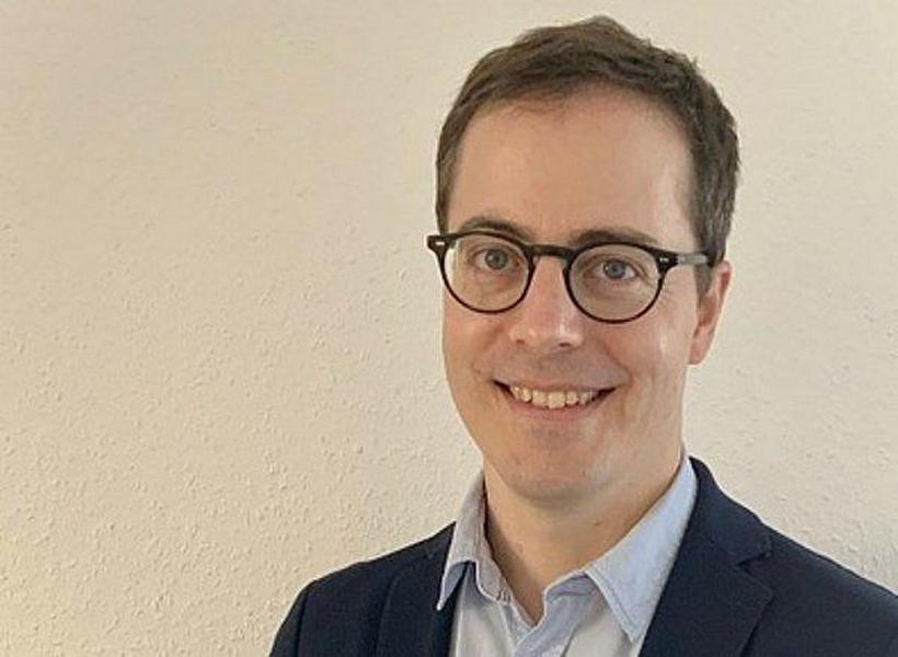 Das Foto zeigt Prof. Dr. rer. nat. Marc Deissenroth-Uhrig, Professur für Erneuerbare Energien an der htw saar.  Er hat eine kurze, dunkelbraune Frisur und helle Haut und lächelt in die Kamera.   Er trägt eine dunkle, runde Brille mit recht dünnem Rahmen.   Er ist mit einem weißen Hemd und einem dunkelblauen Sakko gekleidet