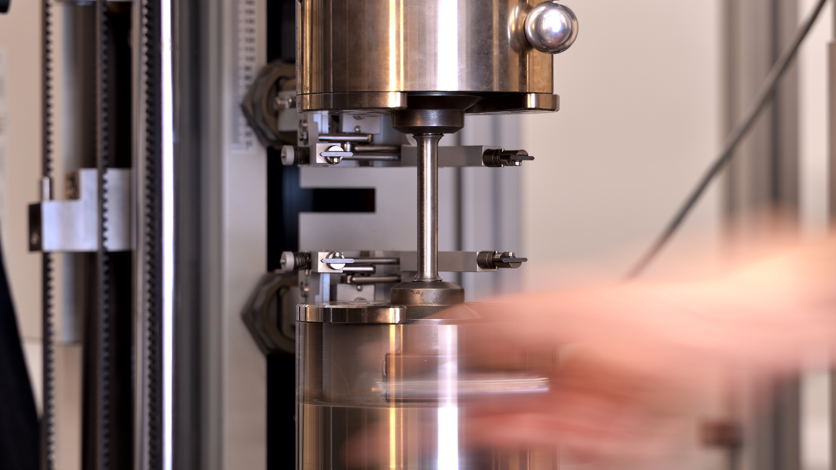 Eine Hand spannt eine Rundzugprobe ein.